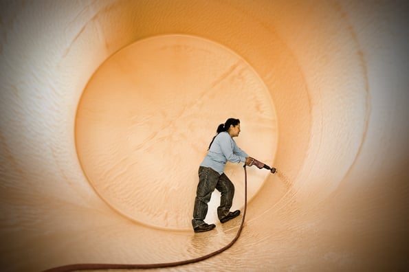 Photo of a worker putting a fitting hole in a chemical tank